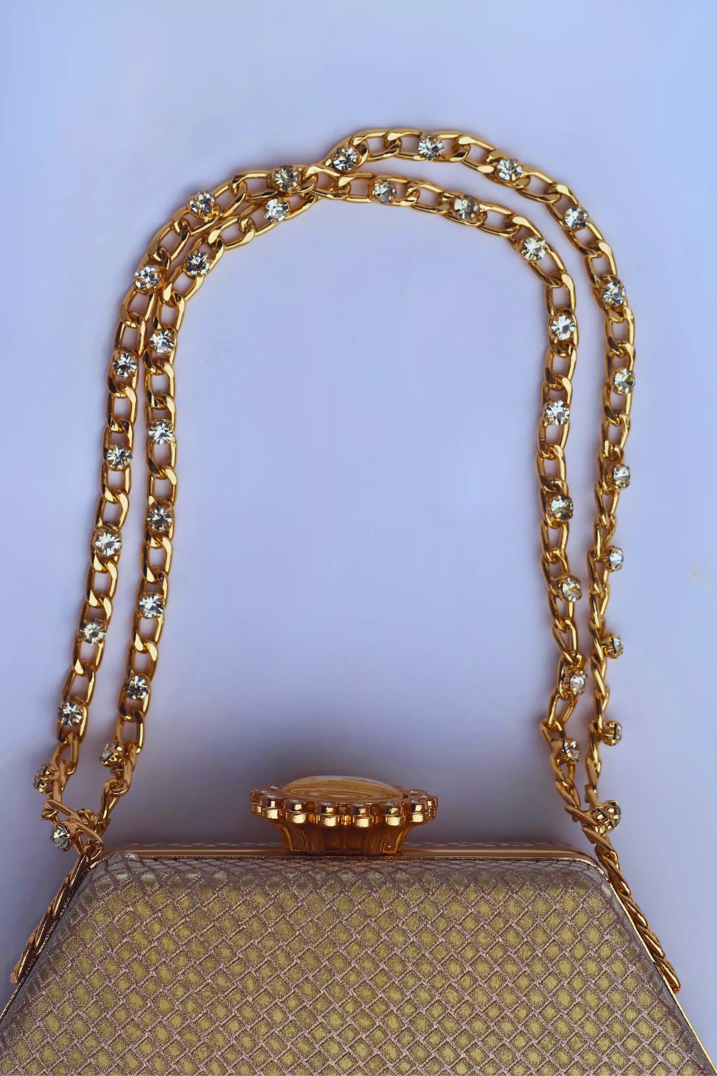 Gold handbag with a decorative chain strap on a white background