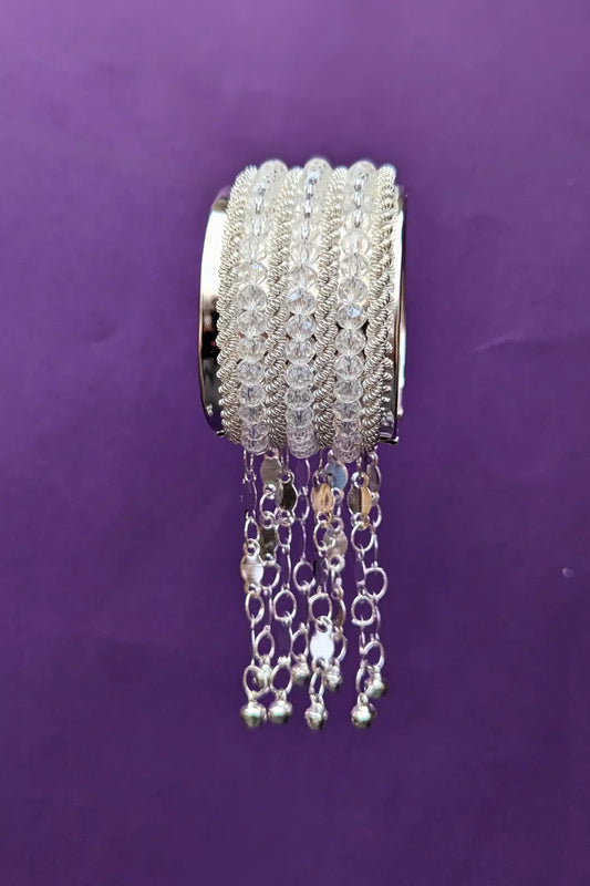 Silver beaded bracelet with dangling elements on a purple background