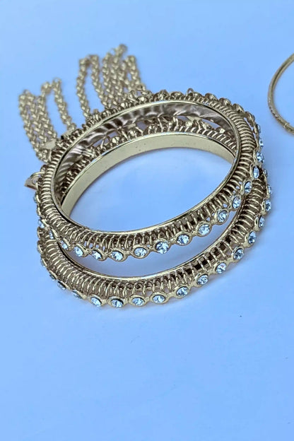 Gold bangles with gemstones on a light blue background