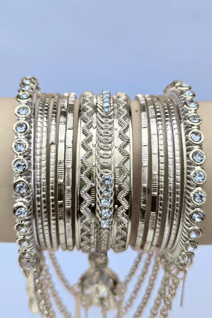 Stack of silver bangles with intricate designs on a light blue background