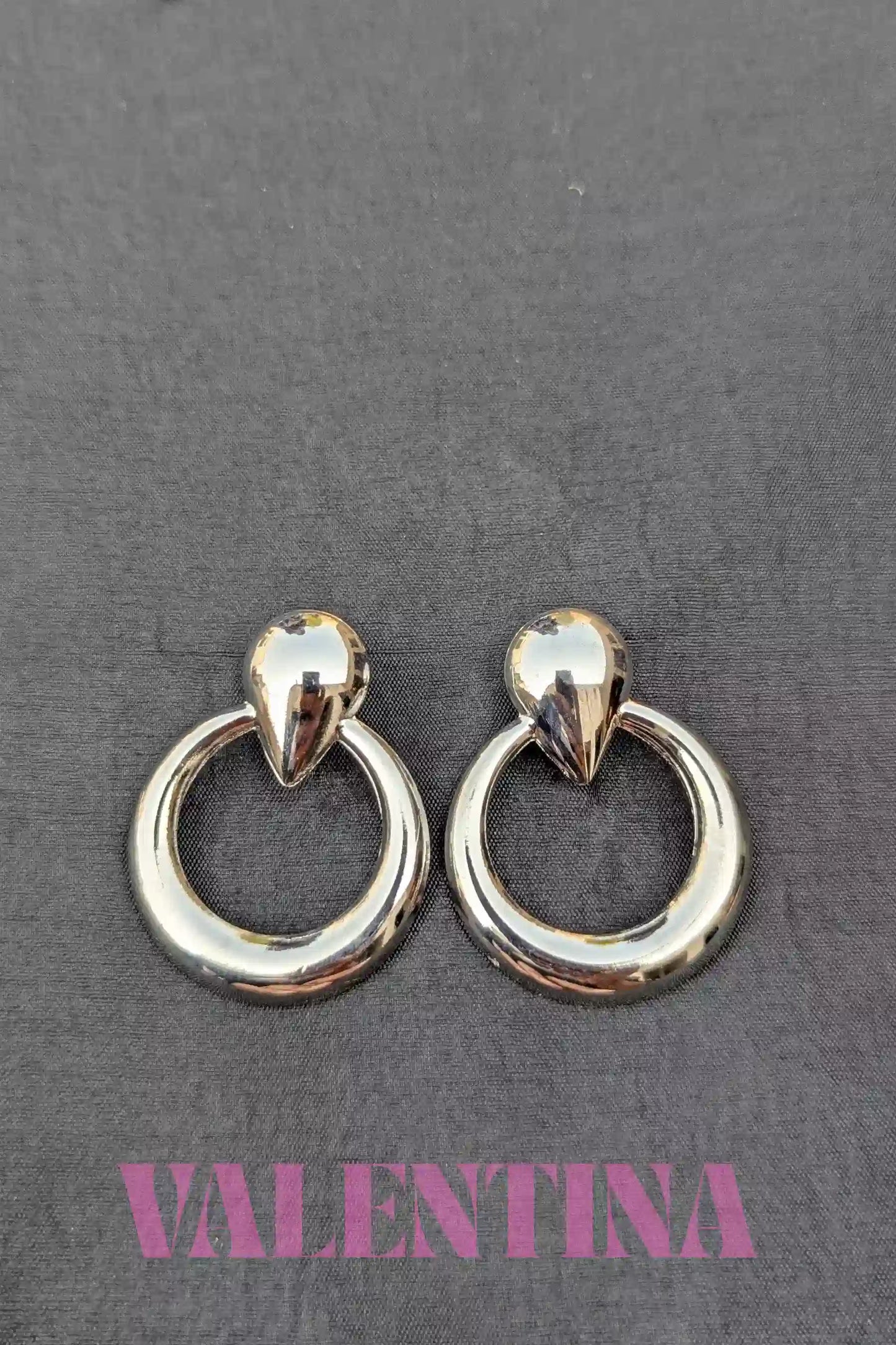 Pair of silver  hoop earrings on a dark background with 'Valentina' branding.