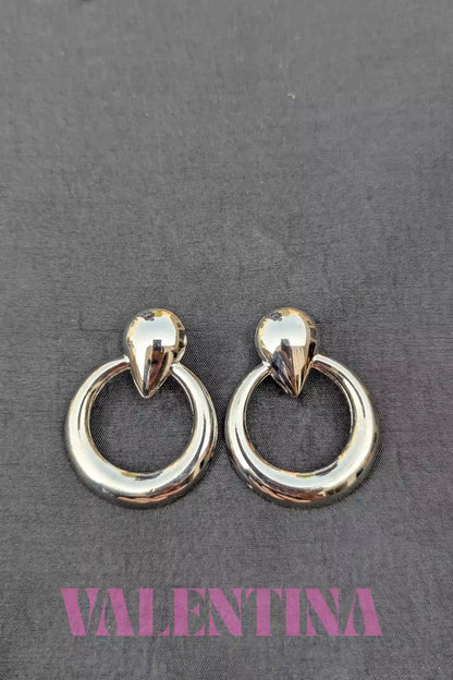 Pair of silver  hoop earrings on a dark background with 'Valentina' branding.