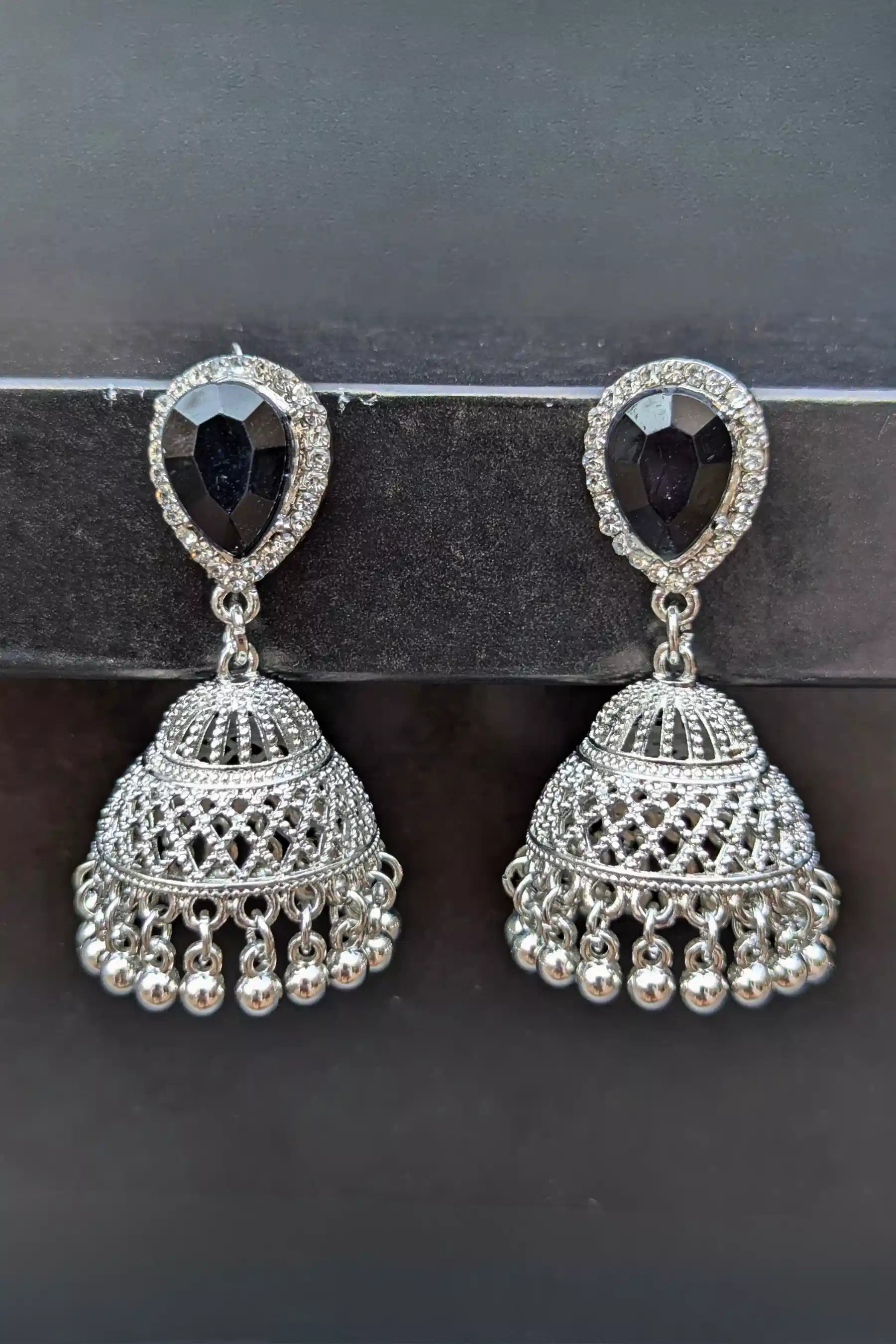 Pair of silver earrings with black gemstones on a dark background
