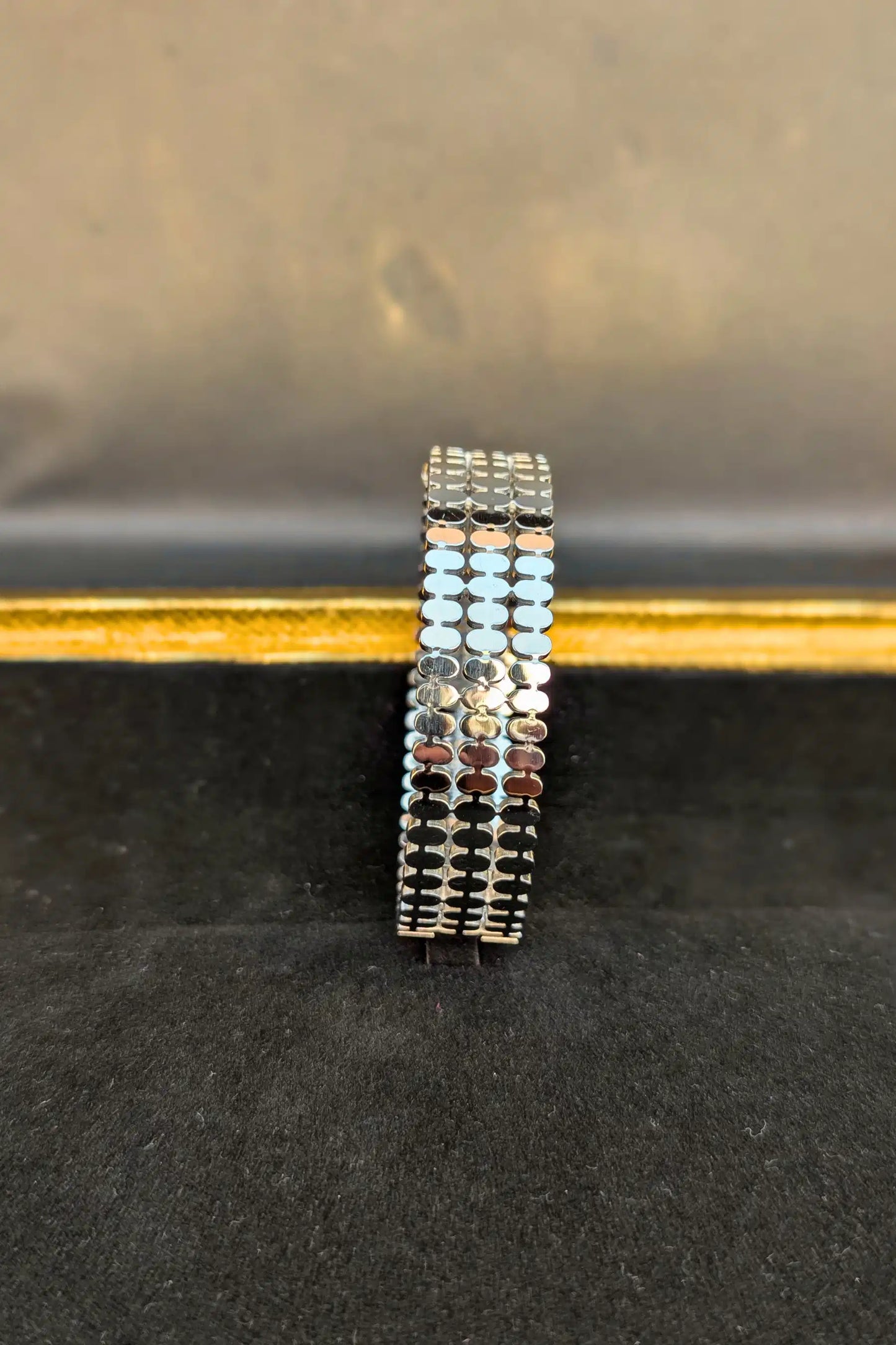 Stack of silver bracelets on a black surface with a blurred background