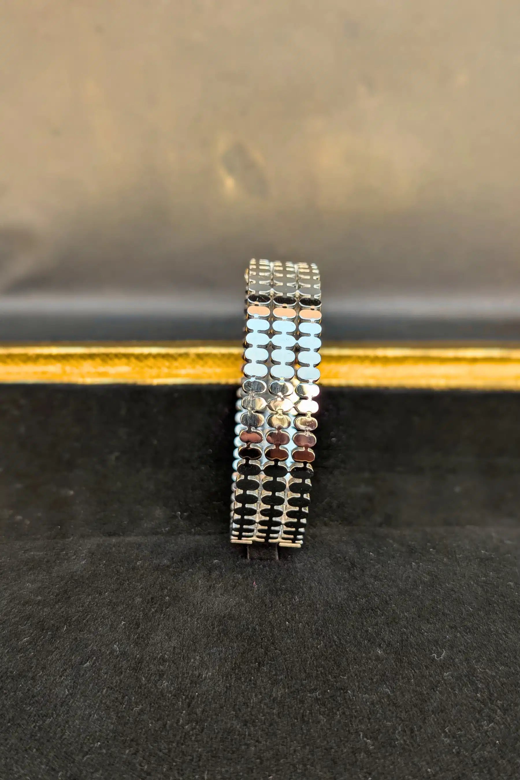 Stack of silver bracelets on a black surface with a blurred background