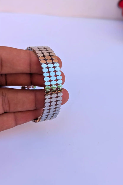 Hand holding a stack of colorful beaded bracelets on a white background