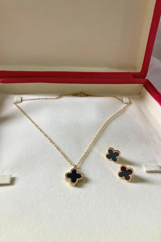 Gold necklace and earrings with black clover design in a jewelry box
