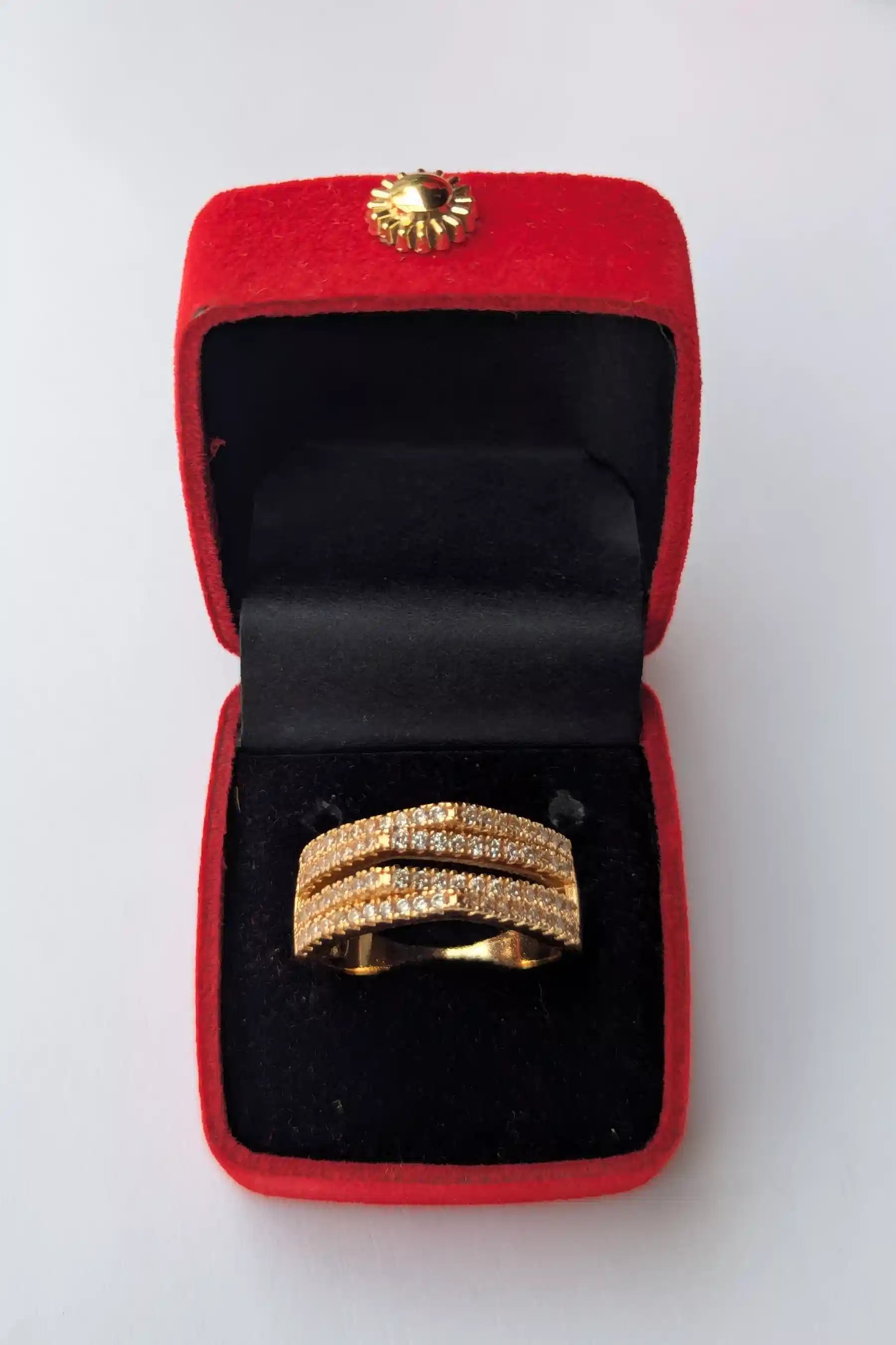 Gold ring in a red jewelry box on a white background