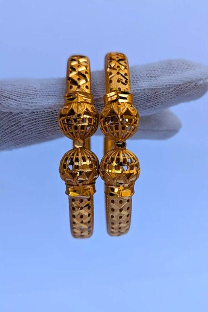 Pair of golden bangles on a light blue background