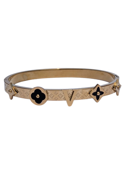 Gold bracelet with black flower designs on a white background