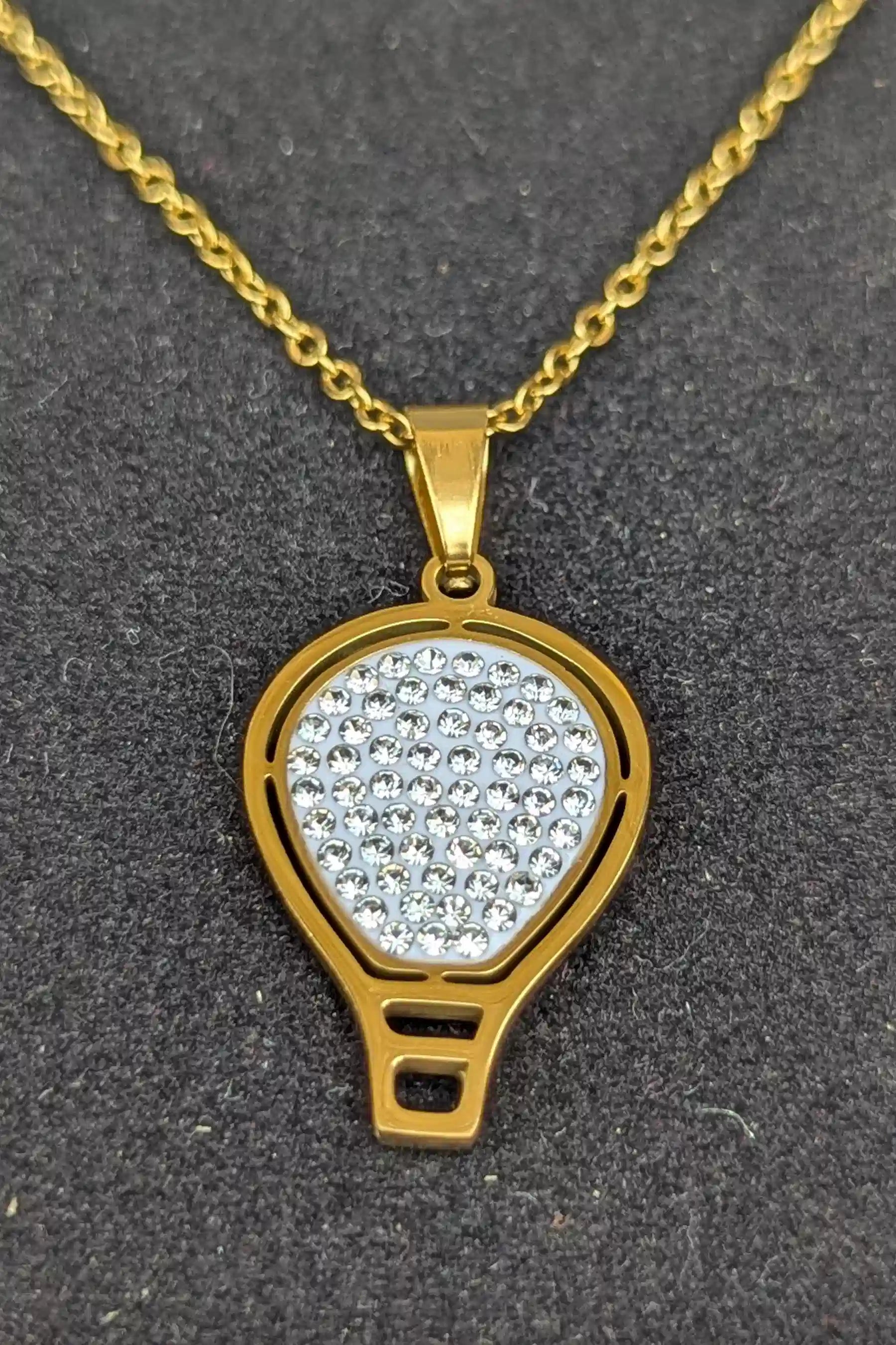 Gold necklace with a diamond-encrusted pendant on a dark background