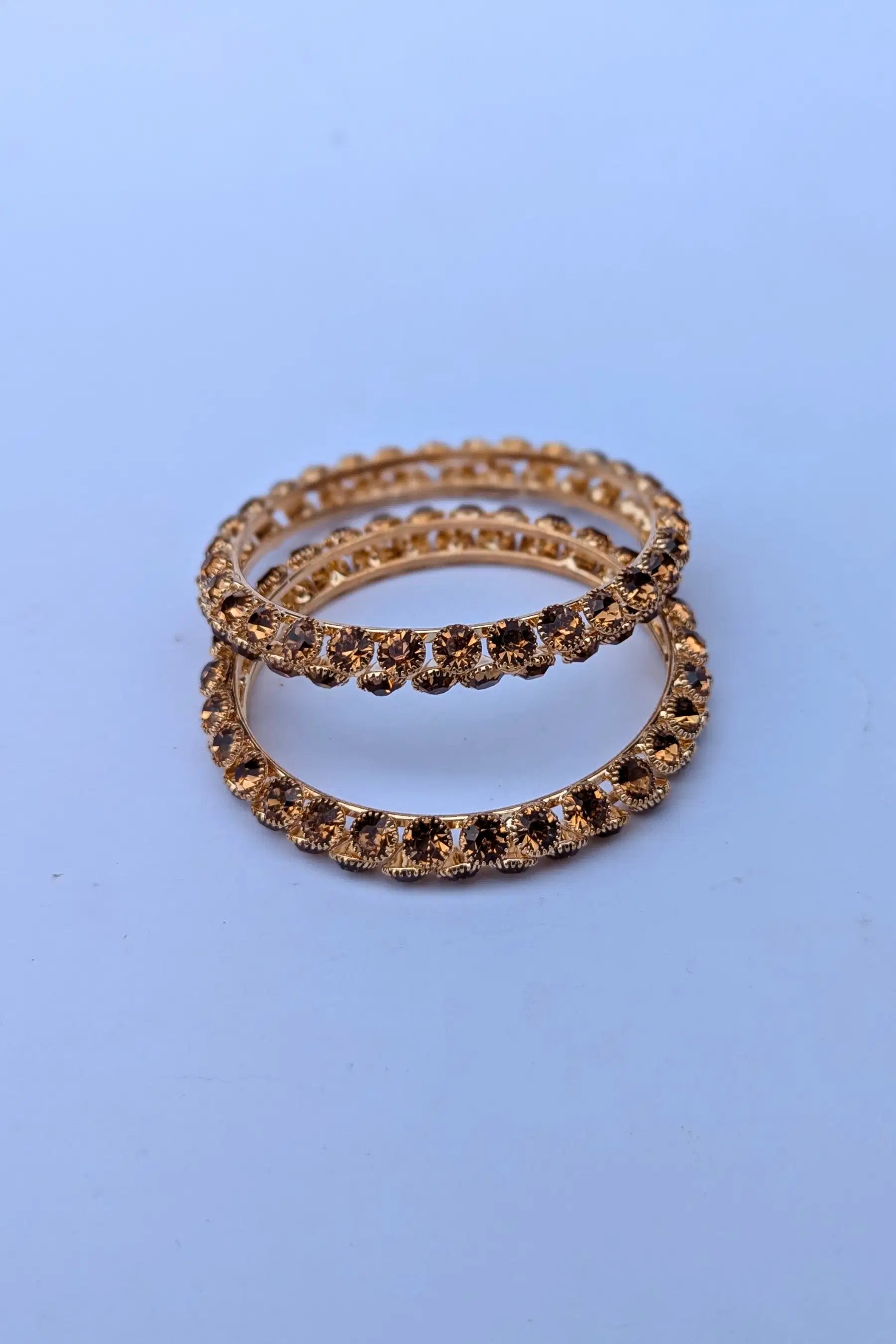 Two gold rings with embedded stones on a light blue background