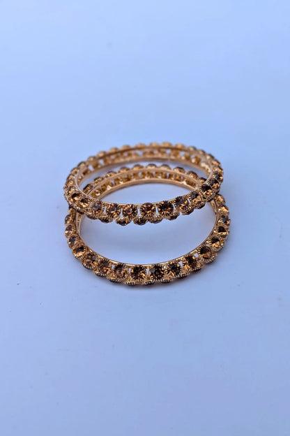 Two gold rings with embedded stones on a light blue background