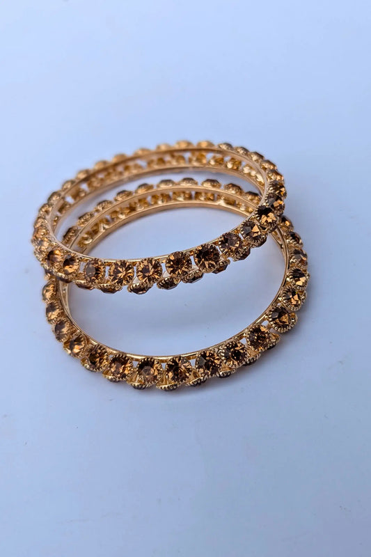 Three gold rings with embedded stones on a light blue background