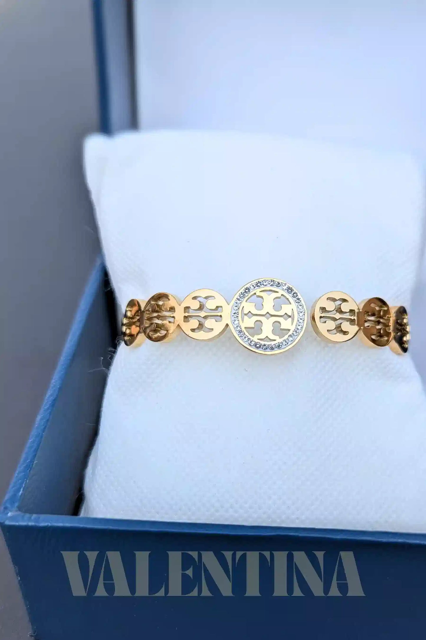 Gold and silver bracelet on a white cushion with 'Valentina' branding.