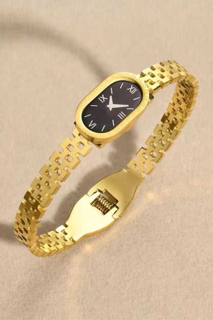 Gold watch with a black face on a beige background